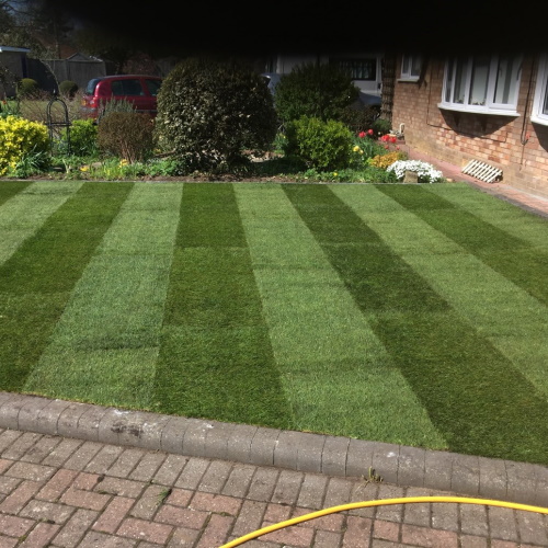 A brick block driveway leading onto a well manicured lawn