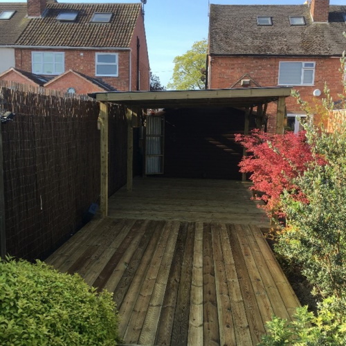 A raised wooden deck under a wooden pergola